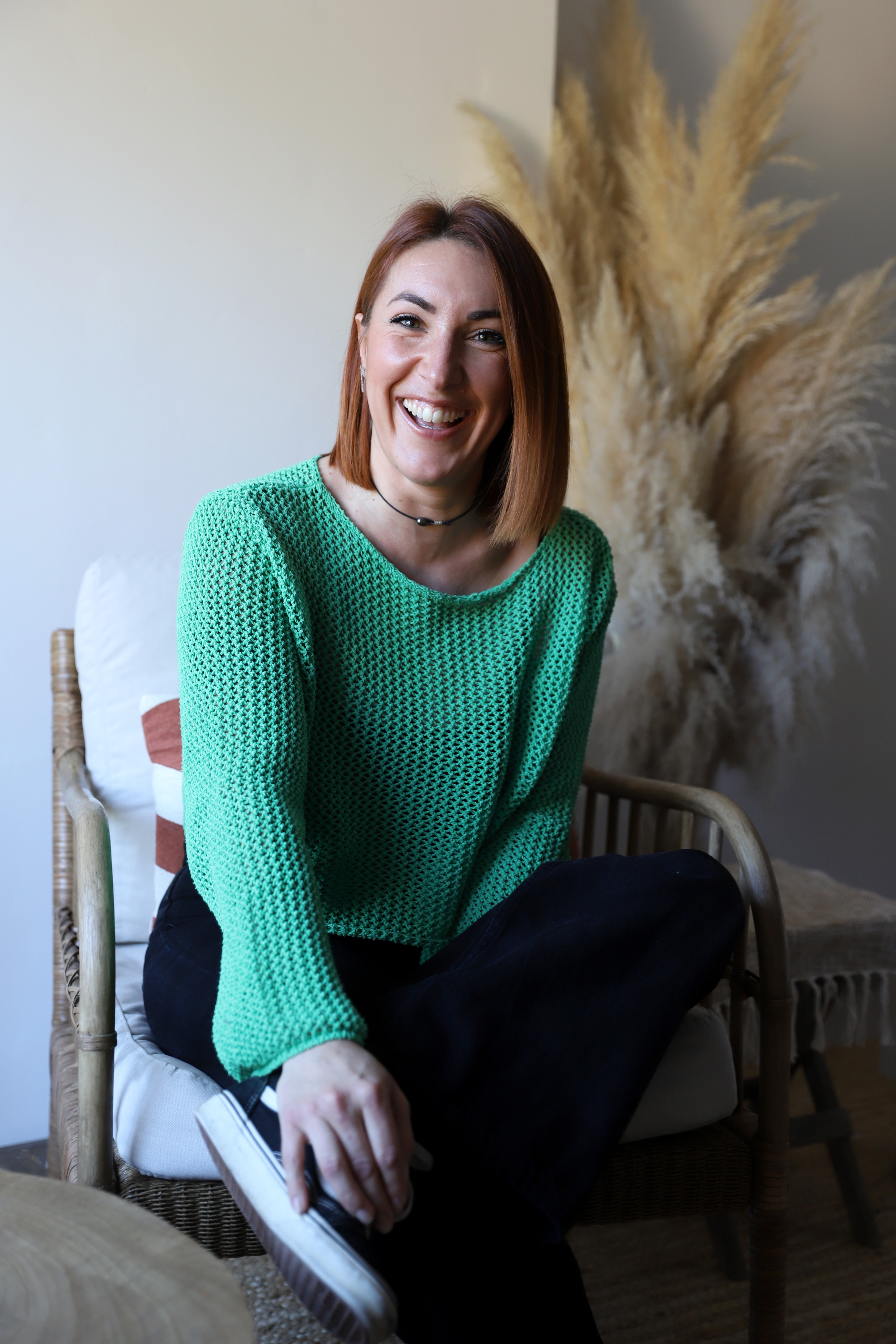 Portrait de Georgie, Digital Strategist, souriante et vêtue d'un pull vert, posant dans un fauteuil avec une décoration moderne en arrière-plan. Le texte sur l'image pose la question 'Fatigué(e) de lutter avec ta communication digitale ?' mettant en avant le thème de l'accompagnement pour les chefs d'entreprise dans le secteur de la beauté.
